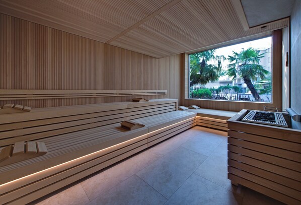 A modern spa area with wooden benches and a large window offering a view of palm trees and buildings.