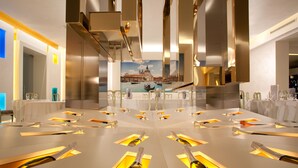 Un espace de salle à manger moderne avec une table centrale ornée de bouteilles et de verres à champagne, entourée de chaises blanches.