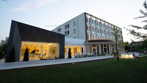 Un bâtiment moderne doté d’une façade en verre, d’une entrée incurvée et d’une pelouse bien entretenue.