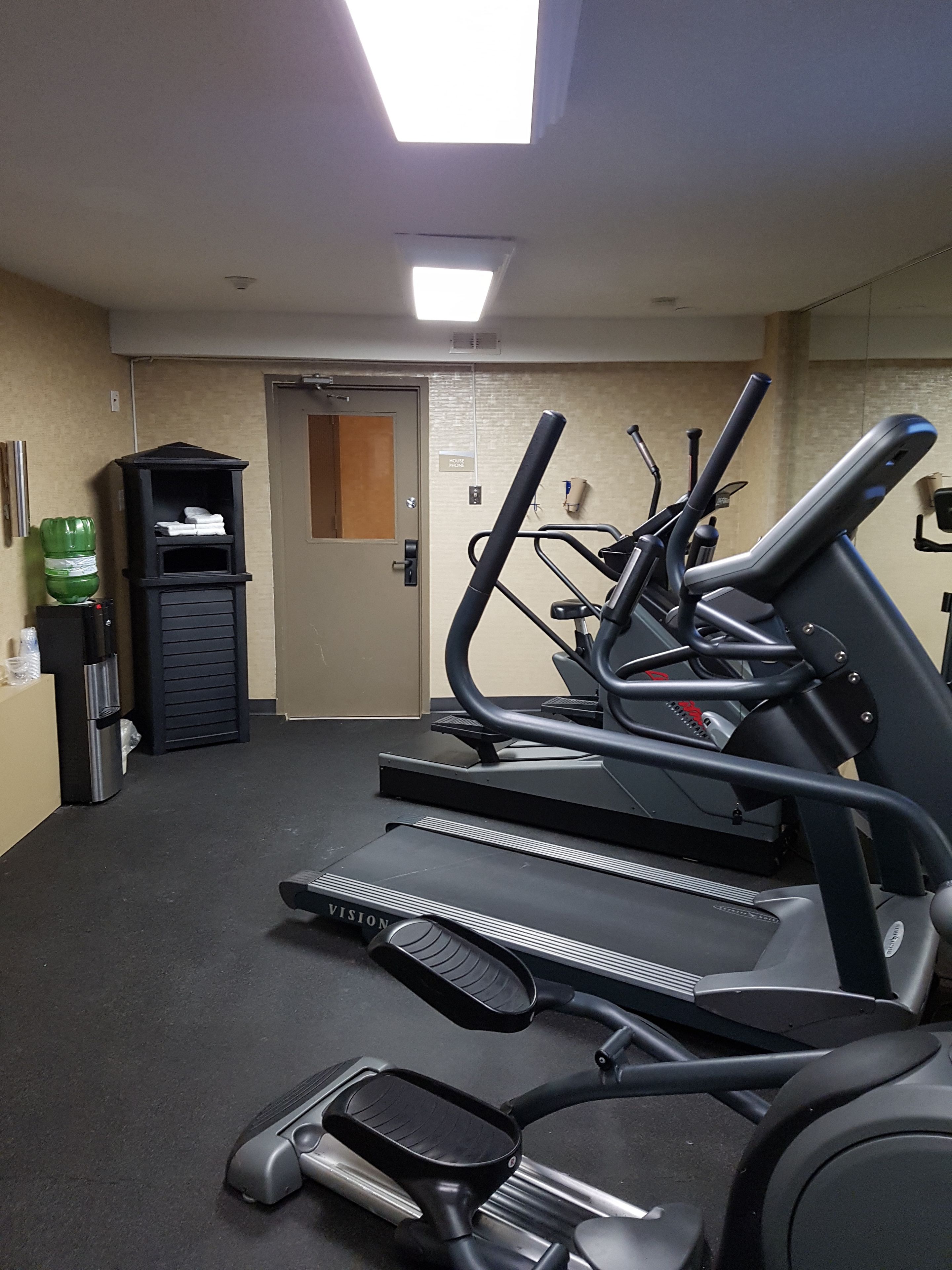 A gym with treadmills, a water dispenser, and a door labeled "House Phone".