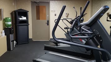 Un gimnasio con cintas de correr, un dispensador de agua y una puerta que dice 'Teléfono de la Casa'.
