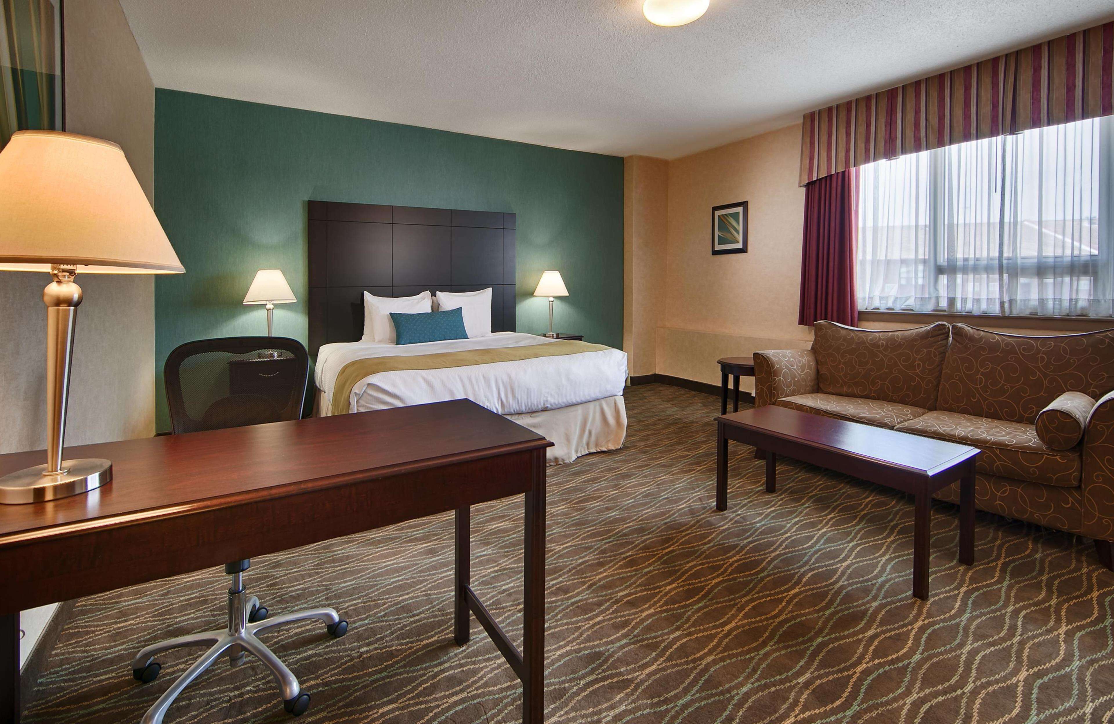 Habitación de hotel con una cama, un sofá, un escritorio y una silla.