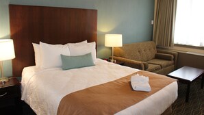 Une chambre d’hôtel avec un grand lit, une chaise, une table et une lampe.