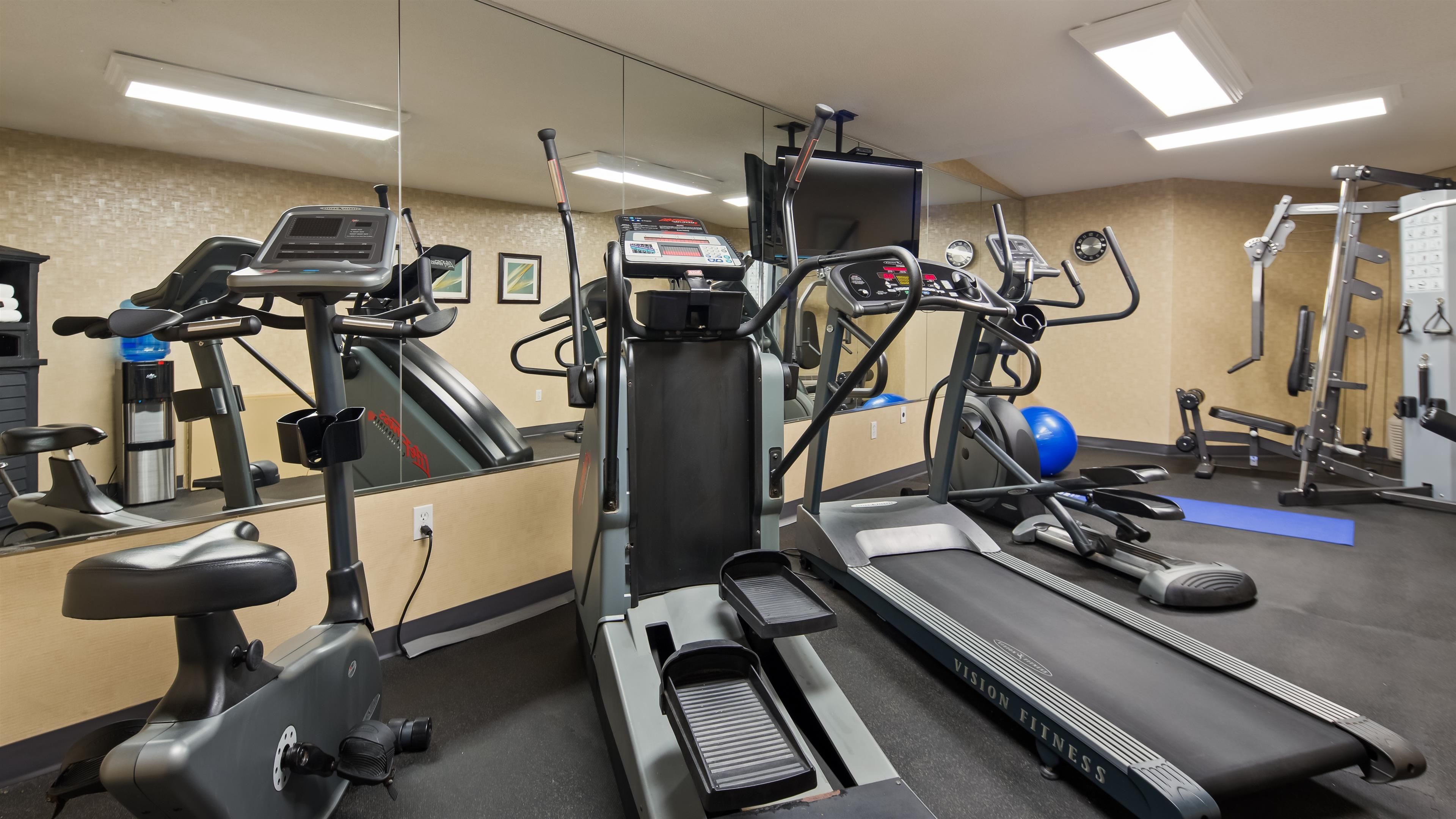 A gym with cardio equipment, weight machines, and a mirrored wall.