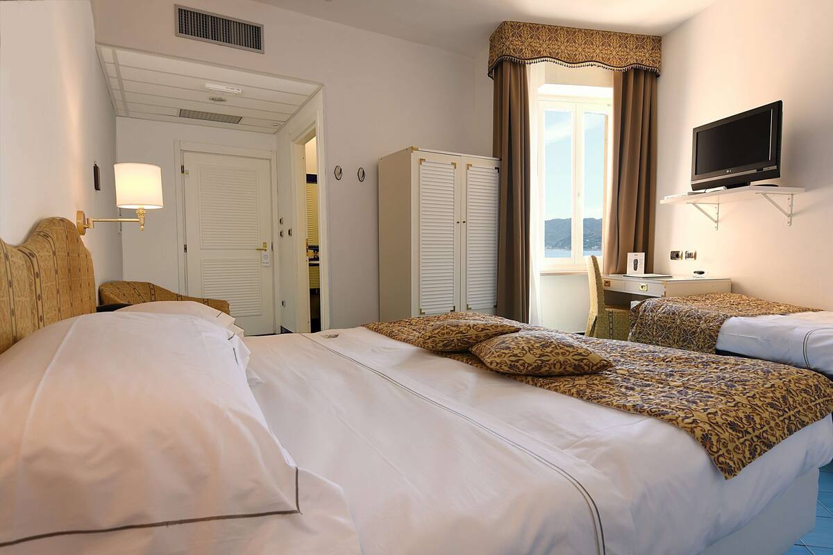 Une chambre d’hôtel avec deux lits, une télévision, une armoire et un bureau.