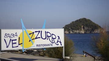 A sign for Bagnì Velazzurra Ristorante with a view of a coastal landscape.
