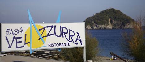 A sign for Bagnì Velazzurra Ristorante with a view of a coastal landscape.