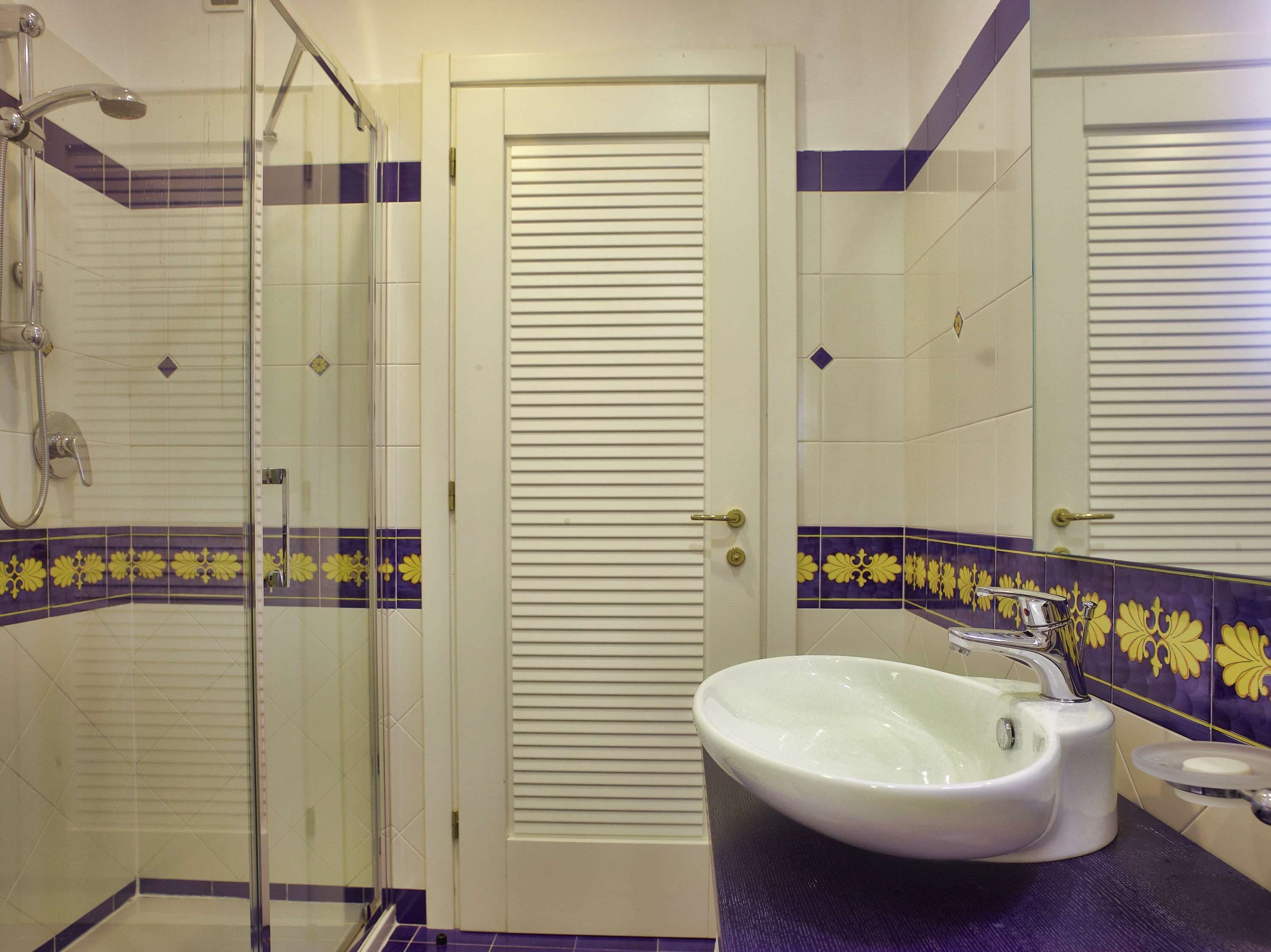 A bathroom with a glass shower enclosure, a white sink, and a toilet.