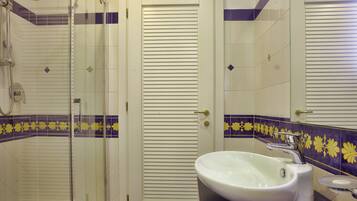 A bathroom with a glass shower enclosure, a white sink, and a toilet.