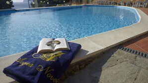 A poolside area with a towel and book, clear pool water, and a view of the sea. - Best Western Hotel Acqua Novella (Spotorno)