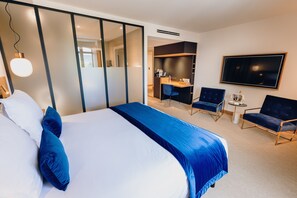 A modern hotel room with a large bed, a desk, and two chairs.