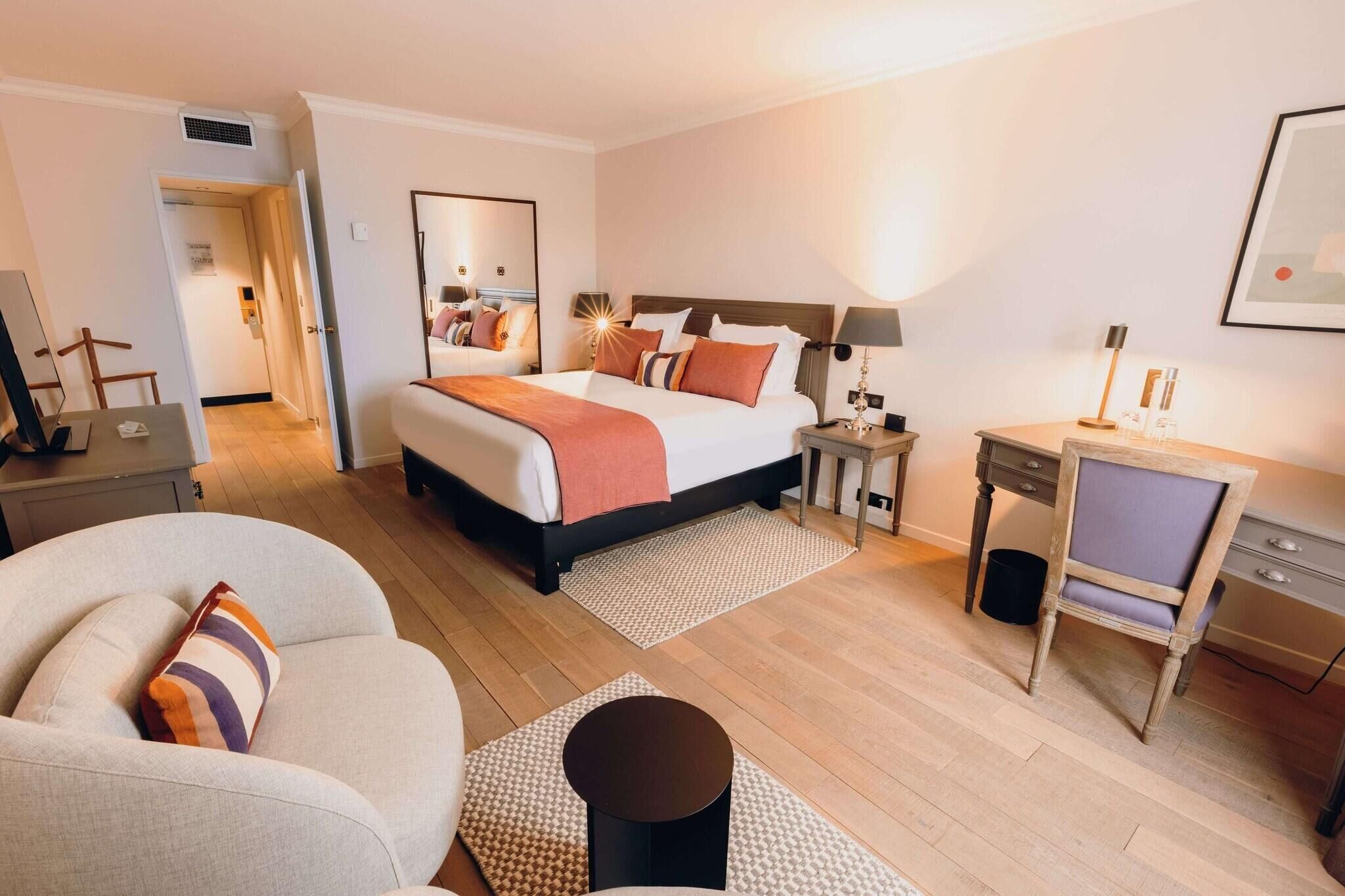 Een hotelkamer met een bed, een bureau, een stoel, een bank en een kleine tafel.