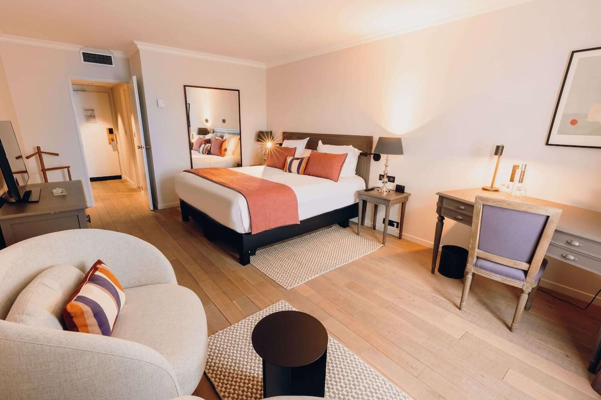 Una camera d'albergo con un letto, una scrivania, una sedia, un divano e un tavolino.