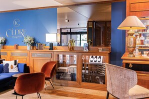 A hotel lobby with a blue wall, wooden reception desk, and seating area with a sofa and chairs.