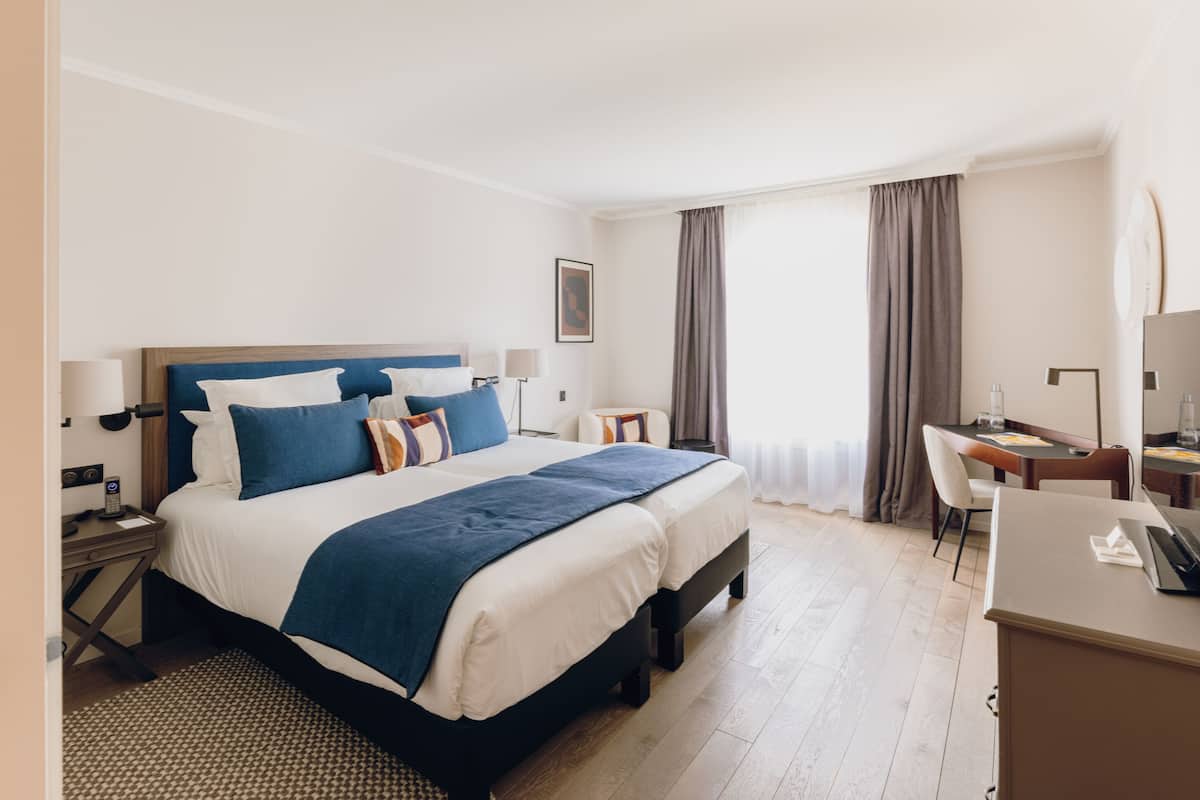 A hotel room with a large bed, a desk, and a chair.
