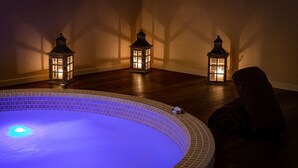 A spa area with a heated pool, three lit lanterns, and a chair. - Cèdre Beaune, A Beauvallon Hotel & Spa (Beaune)