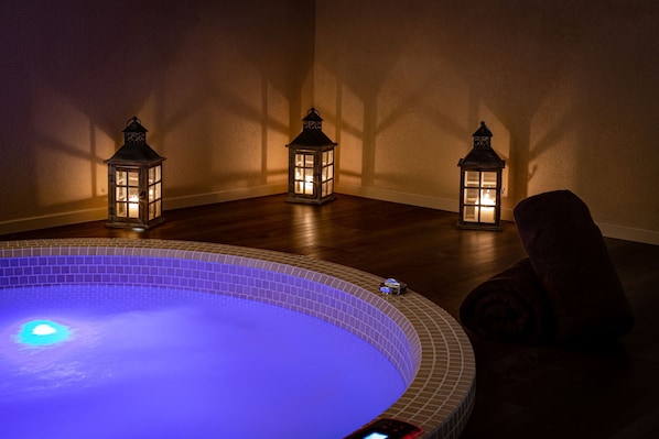 A spa area with a heated pool, three lit lanterns, and a chair. - Cèdre Beaune, A Beauvallon Hotel & Spa (Beaune)