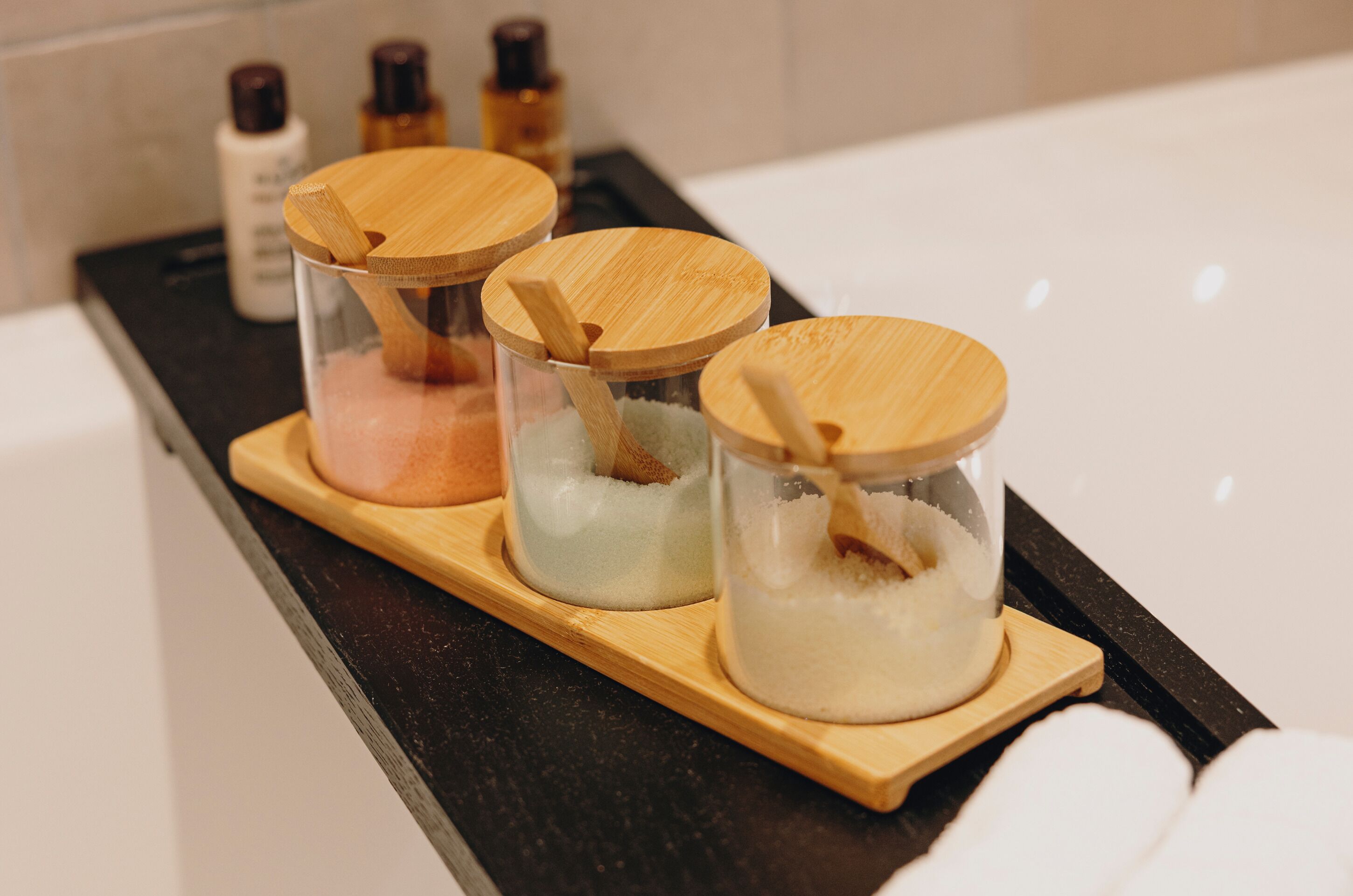 Three glass containers with wooden lids on a tray.