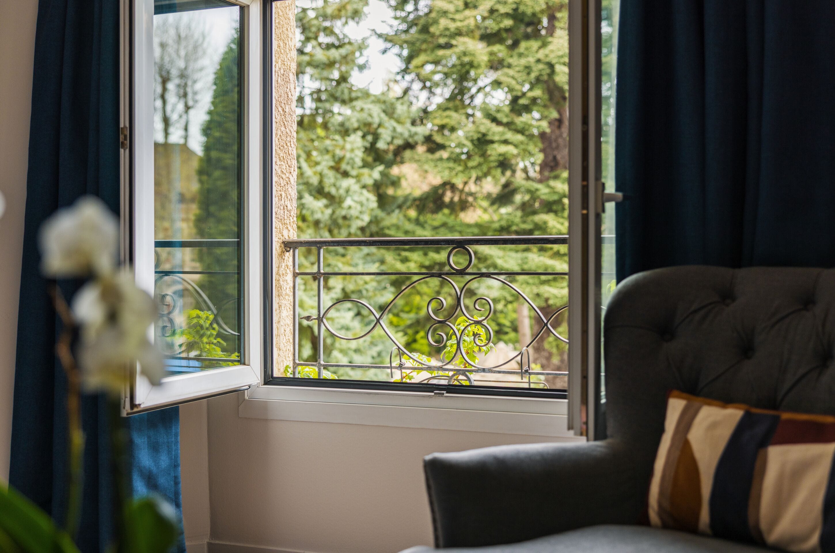 Una habitación con ventana, sofá y vista a árboles.