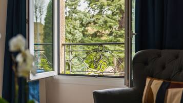 Una habitación con ventana, sofá y vista a árboles.