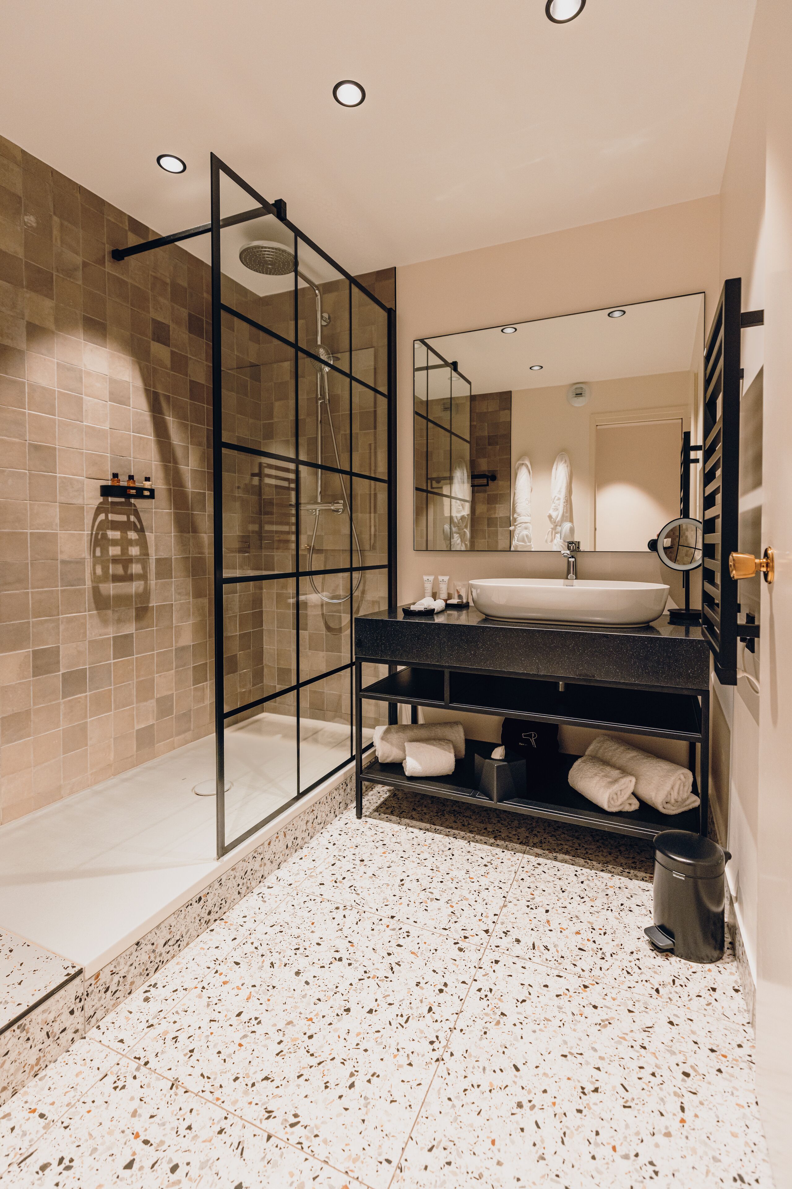 Ein modernes Badezimmer mit einer Glastrennwand zur Dusche, einem großzügigen Waschbecken und einem Spiegel.