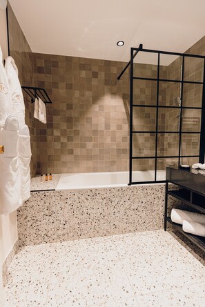 A modern bathroom with a freestanding bathtub, a glass shower enclosure, and a black vanity.