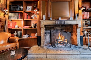 Una sala de estar acogedora con chimenea, sofá de cuero y estanterías de madera llenas de libros y objetos decorativos.