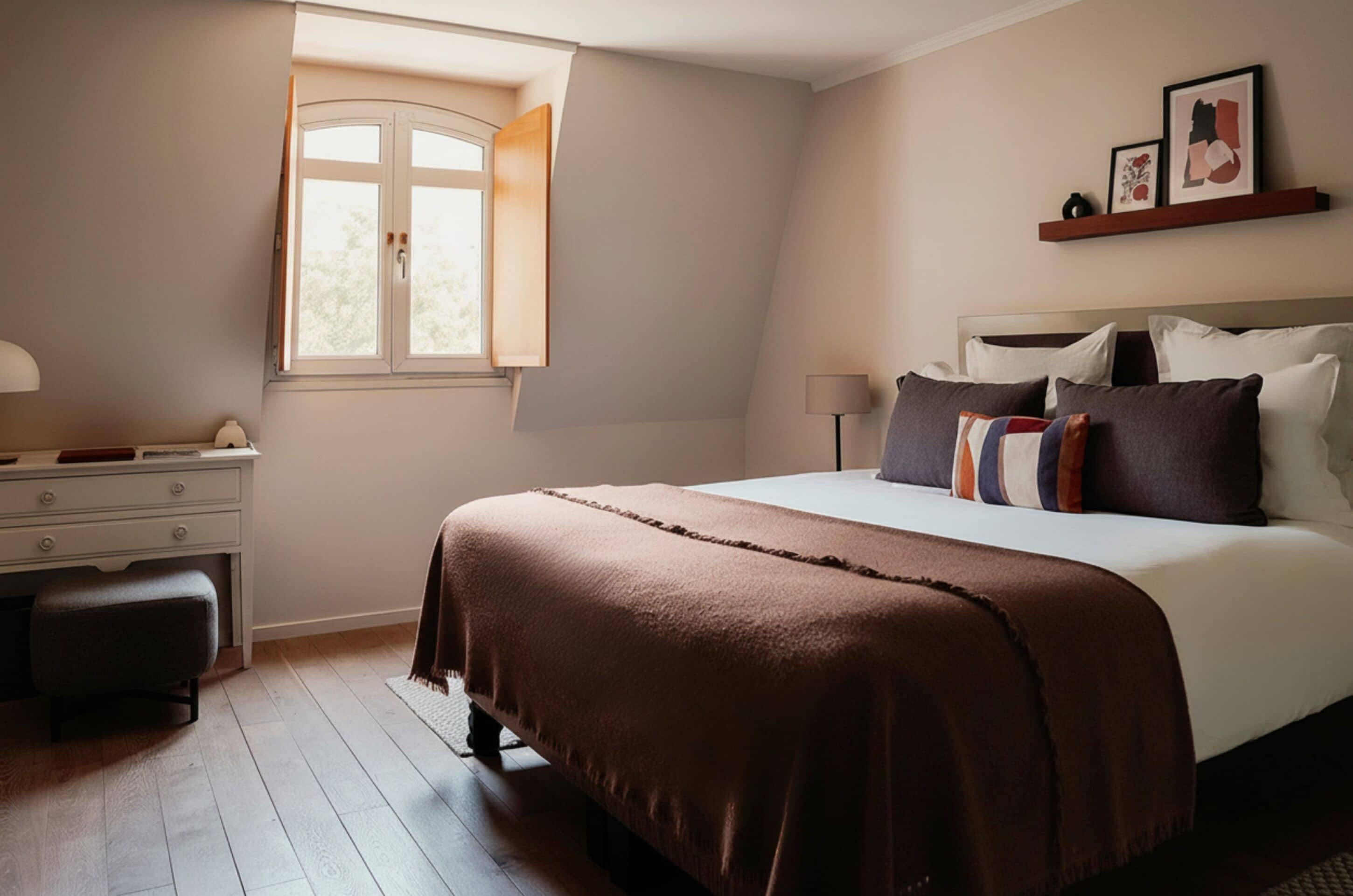 Un dormitorio con cama, escritorio, silla, ventana y mesita de noche.