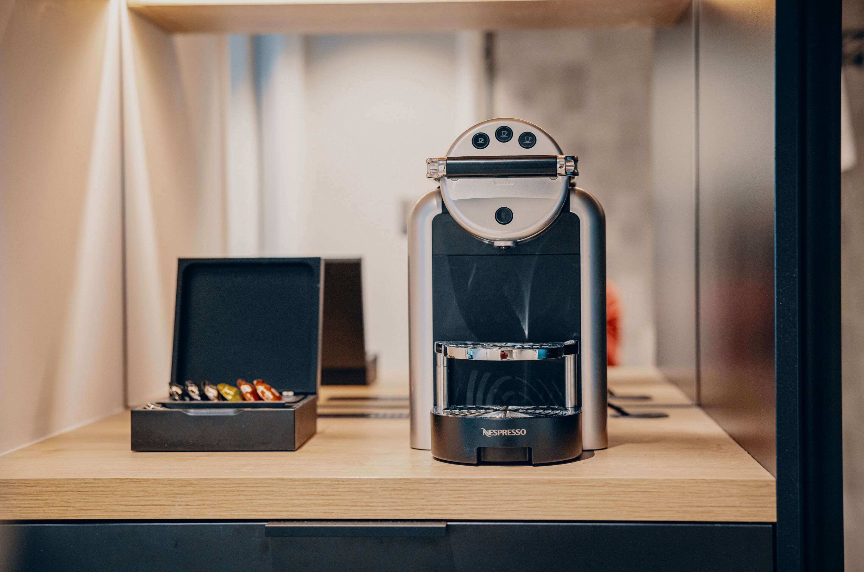 Una cafetera con pantalla y un depósito para cápsulas de café sobre una superficie de madera.