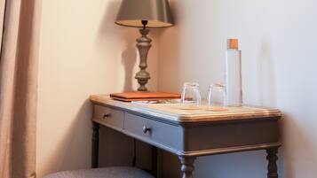 A small wooden desk with a lamp, a glass bottle, and a notebook.