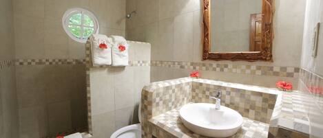 A bathroom with a checkered tile backsplash, a round sink, a toilet, and a shower with a window.