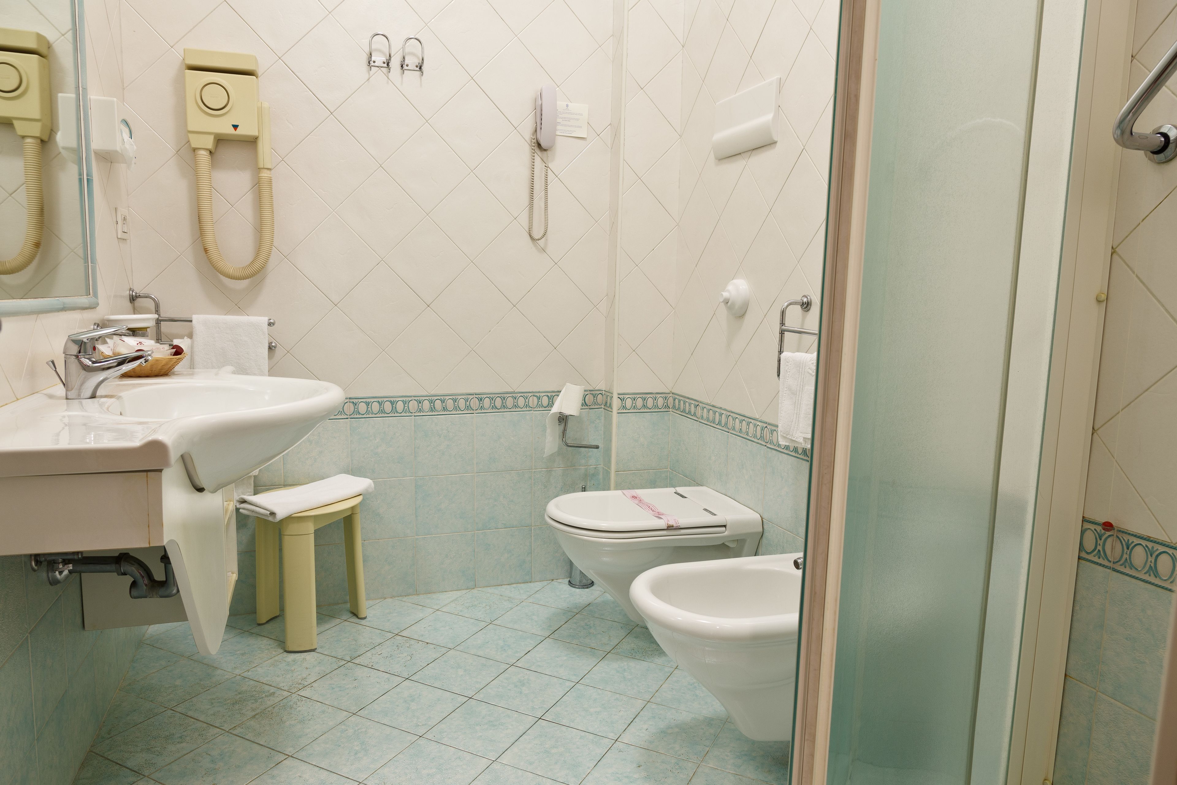 Une salle de bain équipée d’un lavabo, de toilettes, d’un bidet et d’une douche à parois en verre.