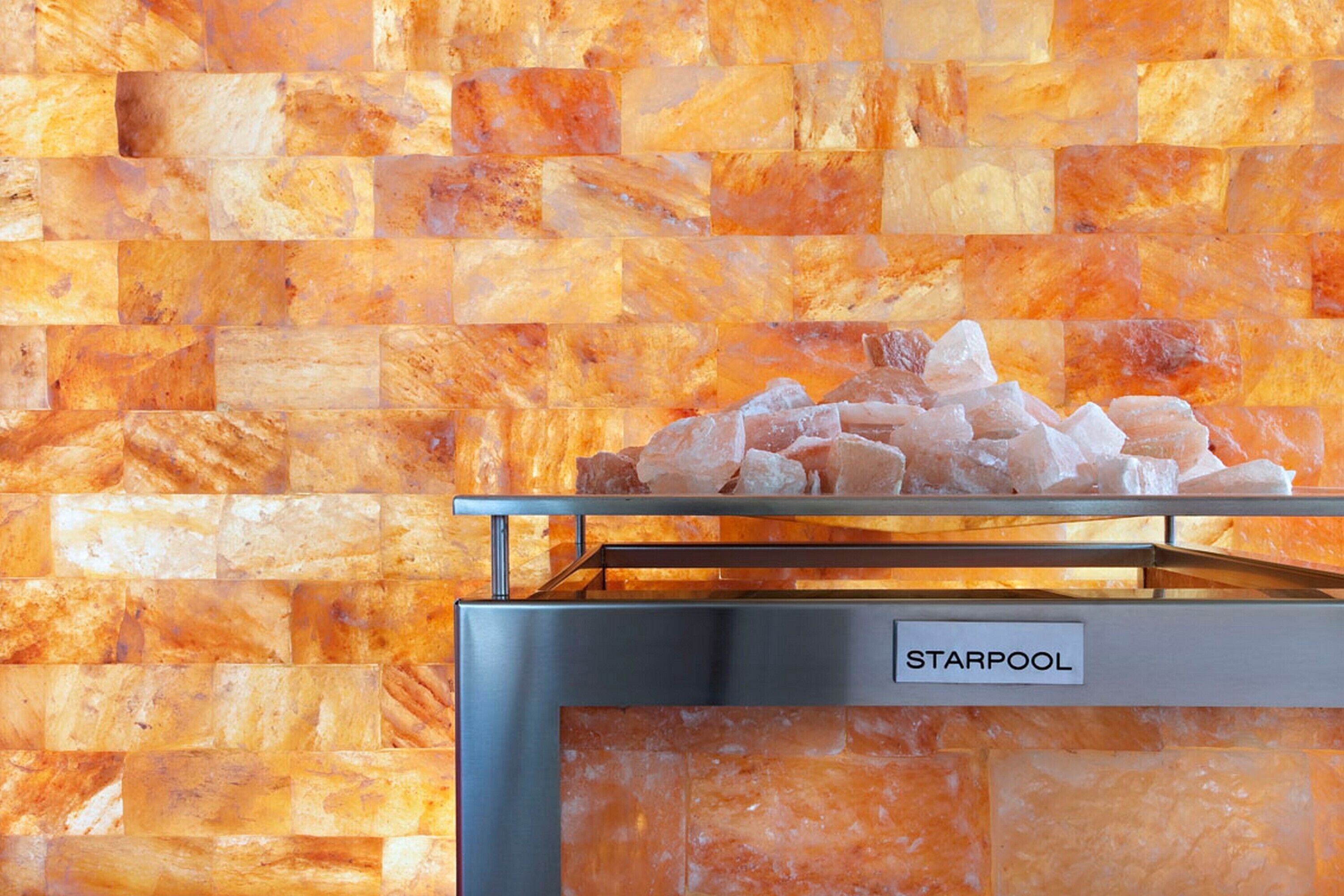 A spa area with a Starpool bath and a wall of orange-toned tiles.