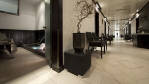 Un hall d’hôtel moderne comprenant un comptoir d’accueil, un espace salon et une sculpture d’arbre décorative.