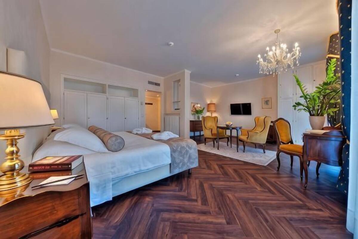 A hotel room with a bed, bedside table, lamp, and a desk with chairs.