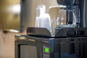 Eine Kaffeemaschine mit digitaler Anzeige, einer Glas-Kaffeekanne und Einwegbechern.