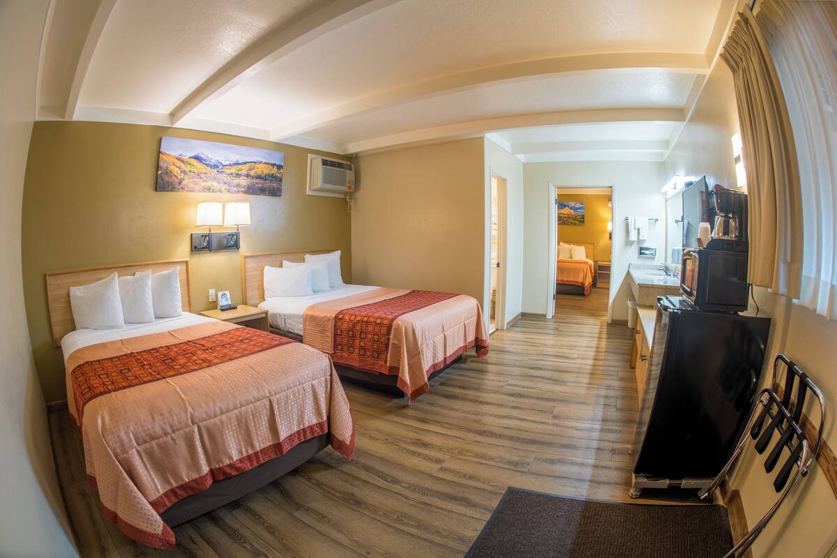 Ein Hotelzimmer mit zwei Betten, einem Schreibtisch, einem Fernseher und einem Bild an der Wand.