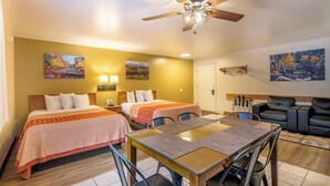 A hotel room with two beds, a dining table, a ceiling fan, and artwork on the walls. - Glenwood Springs Cedar Lodge (Glenwood Springs)