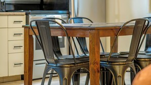 A kitchen with a wooden table and metal chairs, a stove, and a refrigerator. - Glenwood Springs Cedar Lodge (Glenwood Springs)