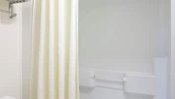 A white bathroom with a shower curtain, a toilet, and a bathtub.