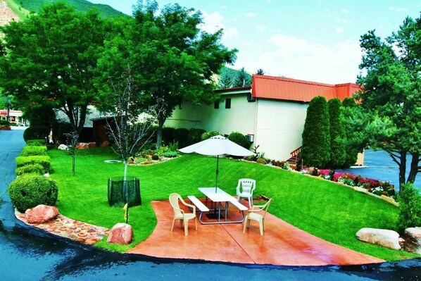Una propiedad residencial con patio empedrado, mobiliario exterior y césped bien cuidado.