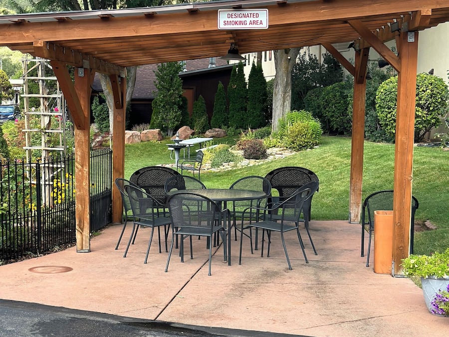 A designated smoking area with outdoor seating under a wooden pergola.