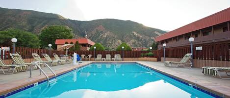 A swimming pool with lounge chairs and a view of mountains.