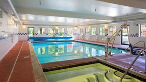 An indoor swimming pool with clear water, a blue slide, and a lifeguard stand. - Glenwood Springs Cedar Lodge (Glenwood Springs)