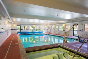Piscina interna com água cristalina, um escorregador azul e um posto de salva-vidas.