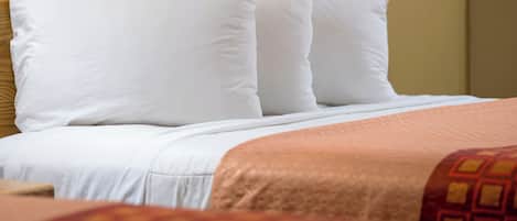 A bed with white pillows and a patterned blanket.