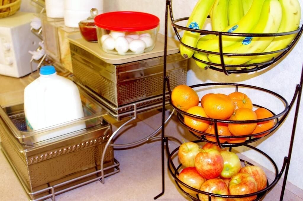 Montaje de bufé con una jarra de leche, huevos, plátanos, naranjas y manzanas.