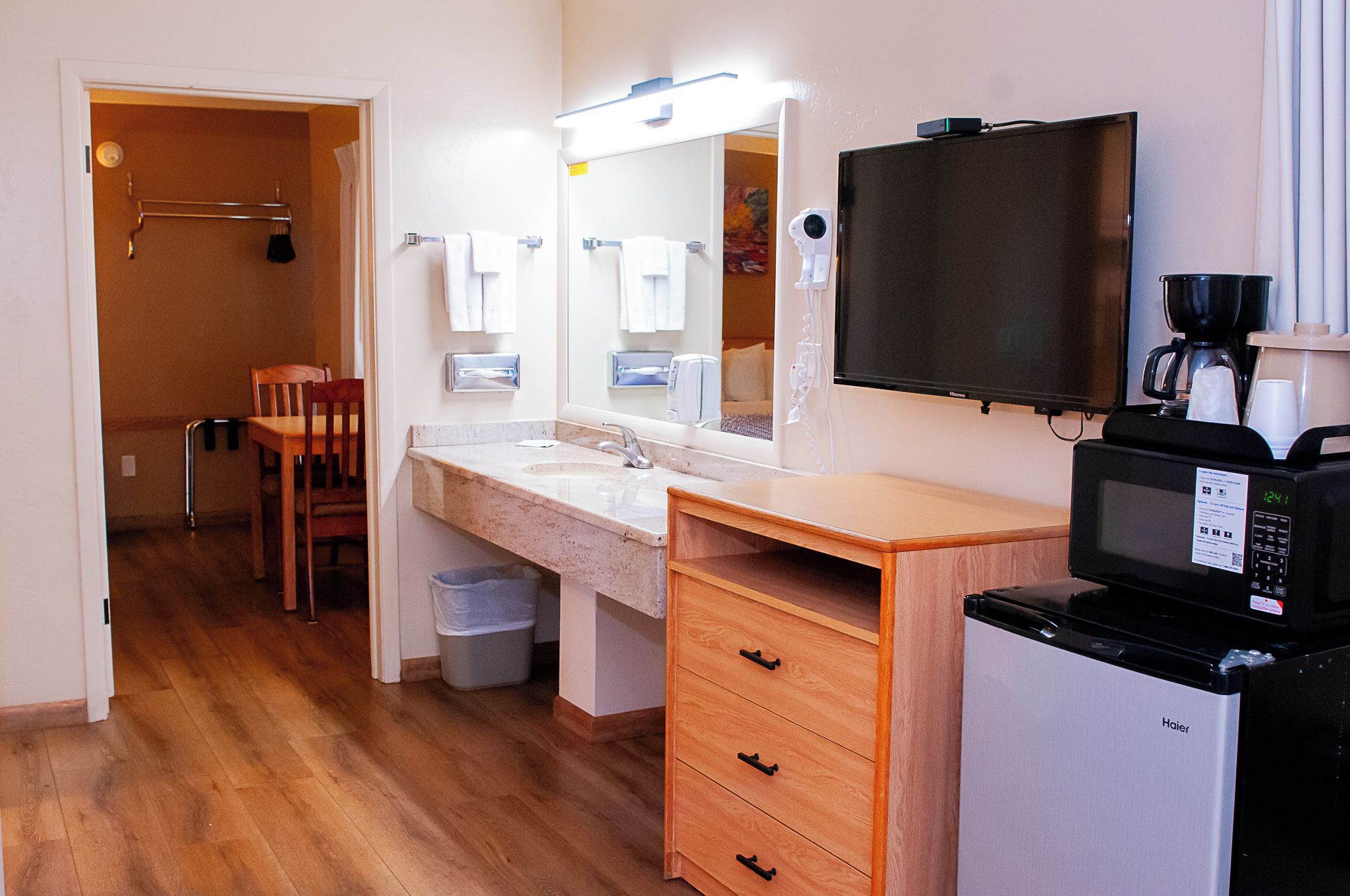 A hotel bathroom with a sink, mirror, vanity, and a television.