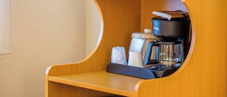 Una kitchenette compacta con cafetera, hervidor y microondas.
