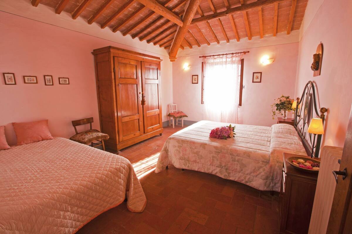 A cozy bedroom with two beds, wooden wardrobe, and a window with curtains.